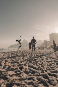 People on beach against sky during sunset