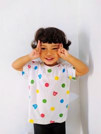 Portrait of smiling girl standing against wall