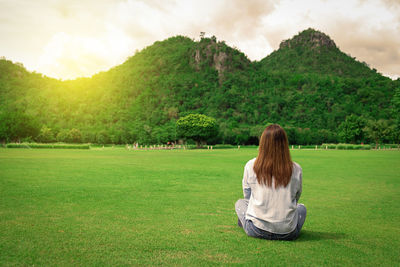 Rear view of woman sitting on land against sky