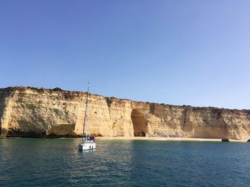 Boat sailing on sea against clear blue sky