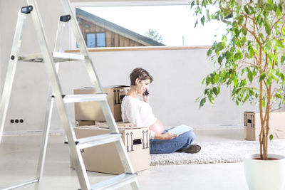 Pregnant woman talking on mobile phone at home