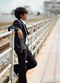Side view of young woman looking away while standing on bridge
