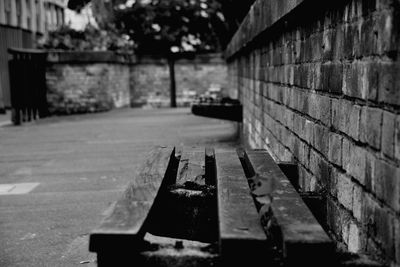 Close-up of empty bench against wall