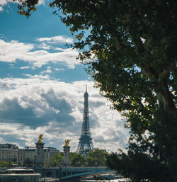 Trees in city against cloudy sky