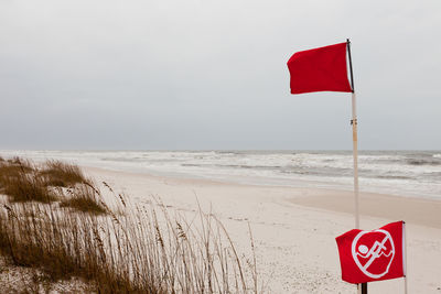 Red flag on beach against sky