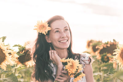 Portrait of smiling young woman against white flowering plants