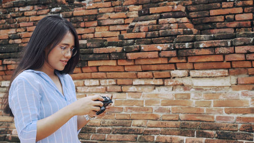 Young woman standing against brick wall