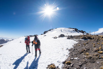 Low angle view of people walking on snow covered mountain against sky