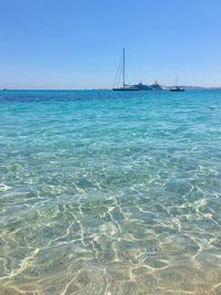 Sailboat in sea against clear blue sky