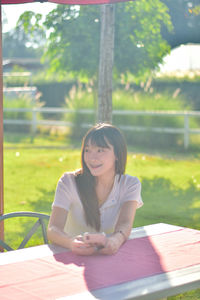 Young woman using laptop while sitting on field