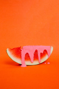 Close-up of watermelon with cream against orange background