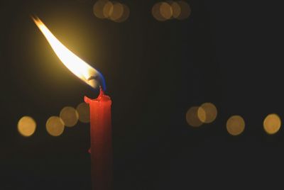 Close-up of illuminated candle in darkroom