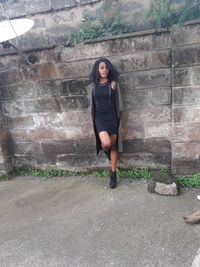 Portrait of young woman standing against wall