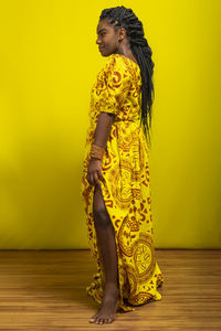 Young beautiful woman standing wearing colorful outfit. isolated against yellow background.