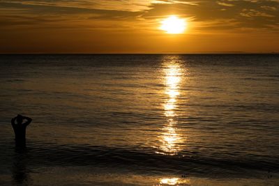 Silhouette man standing on beach against sky during sunset