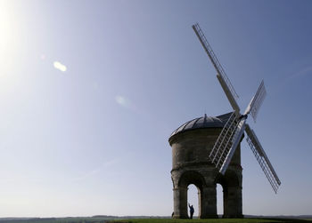 Small windmill on field against sky