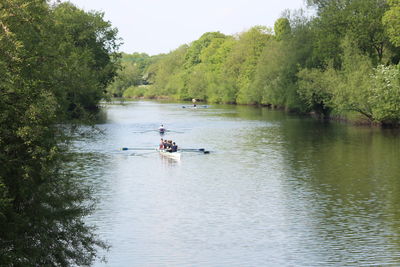 People in boat on river against trees