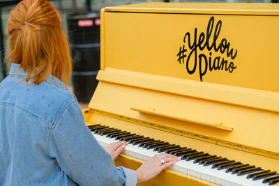 Rear view of woman playing piano outdoors