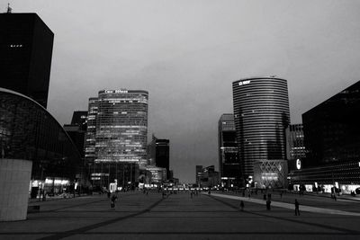 Road amidst buildings against sky at dusk