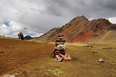 Stacked rocks on field against mountains