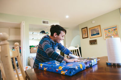 Boy smiles excitedly as he opens up his birthday present