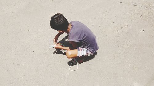 High angle view of boy crouching while playing on street