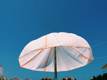 Low angle view of white parasol against clear blue sky