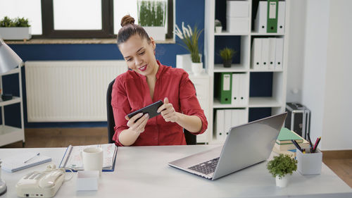 Smiling businesswoman using mobile phone at office
