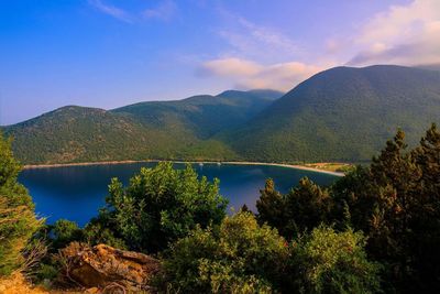 Scenic view of lake and mountains against blue sky