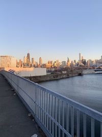 Bridge over river by buildings in city against clear sky