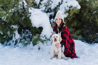 Portrait of woman with dog in snow during winter