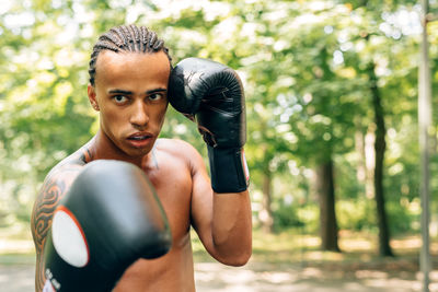 Portrait of shirtless man boxing on street