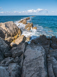 Rocks on shore by sea against sky