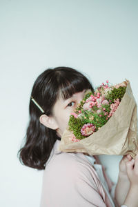 Portrait of woman holding bouquet against white background
