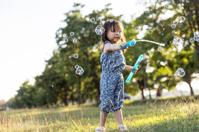 Full length of happy girl playing with bubbles at park