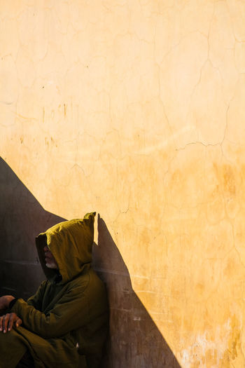 SIDE VIEW OF A MAN SITTING ON WALL