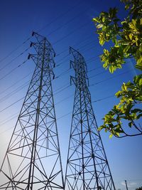 Low angle view of electricity pylon against blue sky