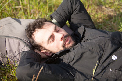 High angle view of man sleeping on grassy field during sunny day