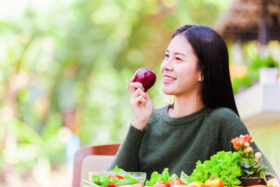 Young woman holding apple against blurred background