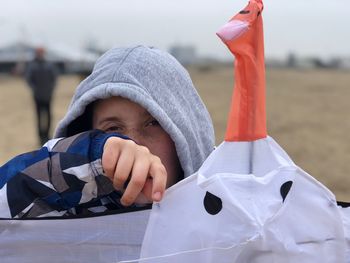 Close-up portrait of boy holding kite while standing on field