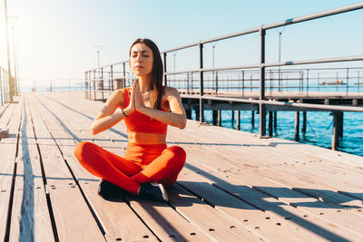 Portrait of young woman sitting on pier