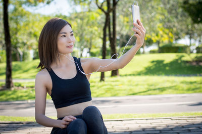 Young woman using mobile phone while sitting on camera