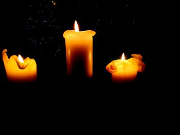 Close-up of lit candle against black background