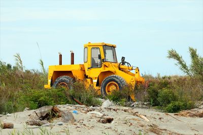 Yellow big bulldozer on the sea shore to move the sand and clean up before the tourists arrive