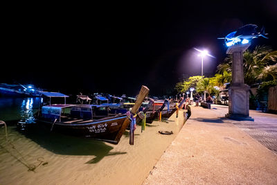 People on boats moored at sea against sky at night