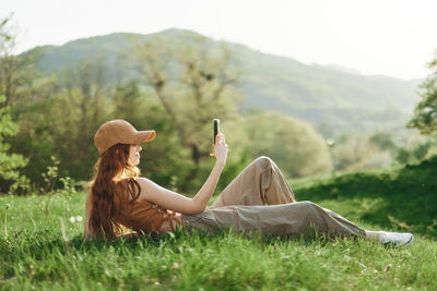 Rear view of woman sitting on grassy field