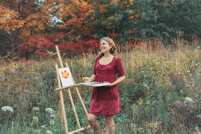 Portrait of smiling young woman standing against plants