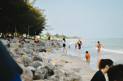 People at beach against clear sky