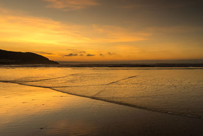 Scenic view of beach against sky during sunset