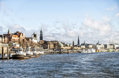 View of buildings at waterfront against cloudy sky